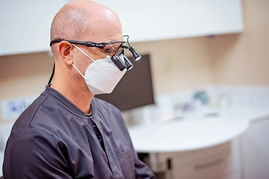 A dentist wearing magnifying loupes and a mask