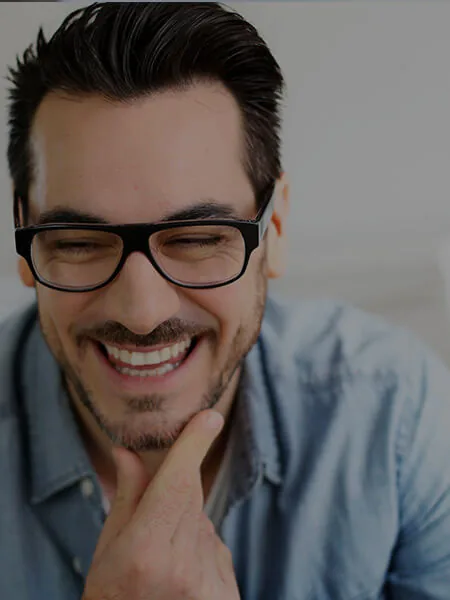A man laughing, holding his chin